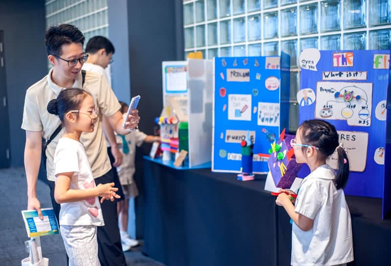 A child presenting her invention project to a visiting family